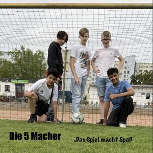 Fünf Jungs posieren als Fussballer mit Ball in einem Fußballtor.