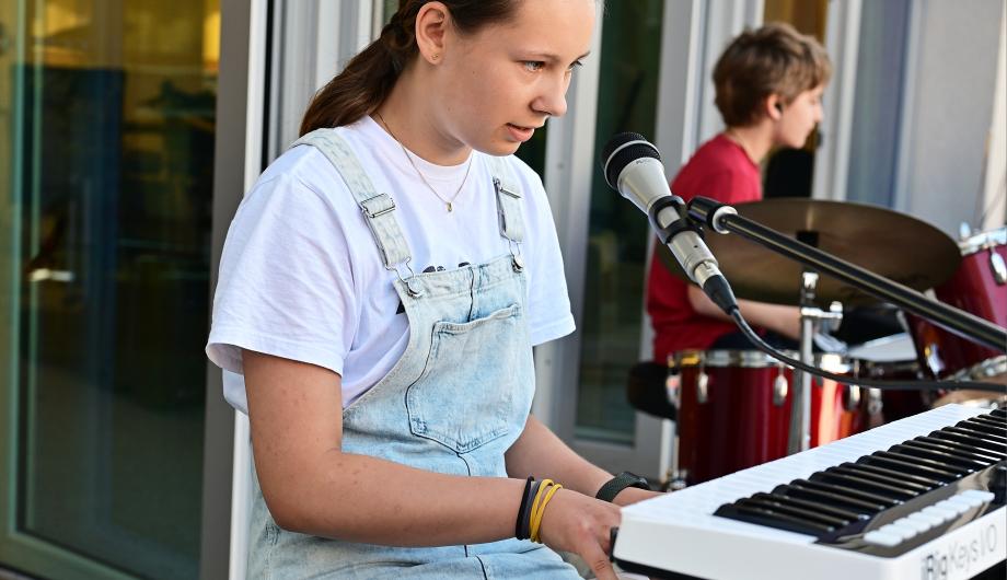 Eine Jugendliche spielt Keyboard auf der Terassenbühne der Städtischen Musikschule Potsdam. Es ist sommerlich bunt.