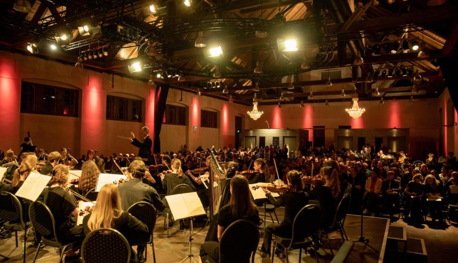 Beim Abschlusskonzert von Jugend Musiziert sehen wir über ein Orchester den Dirigenten und das Publikum in der festlichen Potsdamer Schinkelhalle
