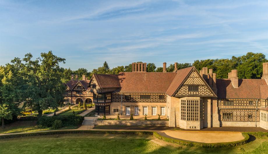 Auf dem Foto ist im Sonnenlicht das Schloss Cecilienhof im Neuen Garten unter strahlend blauem Himmel zu sehen.