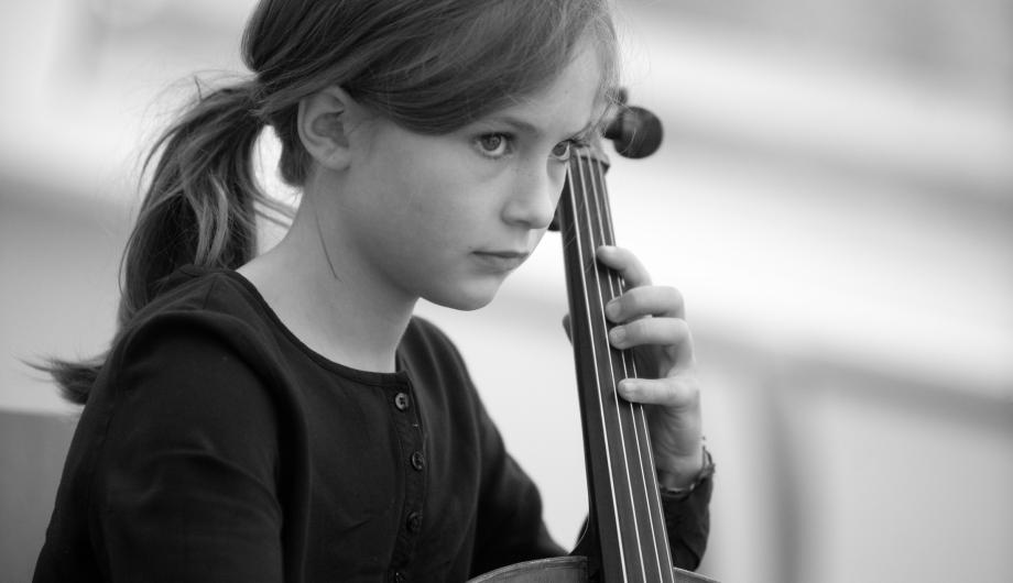 Schwarz-Weiss Bild einer jungen Cellistin - ganz versunken im Spiel