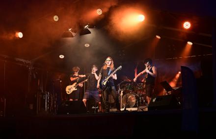 Eine wilde jugendliche Rockband tobt bei mächtiger rötlicher Bühnenbeleuchtung