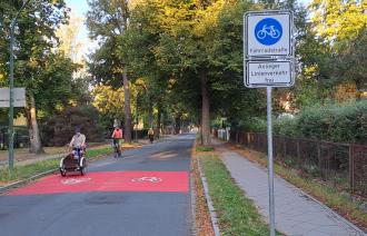 Rote Markierungen auf der Stahnsdorfer Straße und Verkehrsschilder zeigen den Beginn der Fahrradstraße an. 