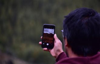 Ein Mann geht mit einem Mobiltelefon in der Hand durch die Natur.