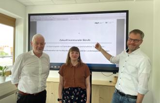 Mitarbeitende der Fachhochschule sowie der Stadt Potsdam stellen vor einem Bildschirm ihr Projekt vor.