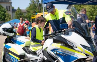 Ein Polizist erklärt einem Jungen die Motorräder der Polizei.