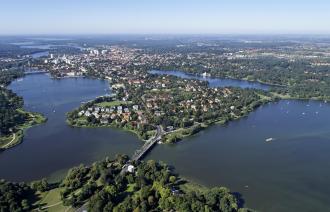 Das Bild zeigt Potsdam aus der Vogelperspektive - vorn die Glienicker Brücke, dahinter die Berliner Vorstadt, umrahmt von der Seenlandschaft und den UNESCO-Welterbeparks.