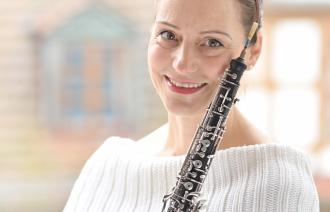 Eine Musikerin lächelt und hält ihre Oboe