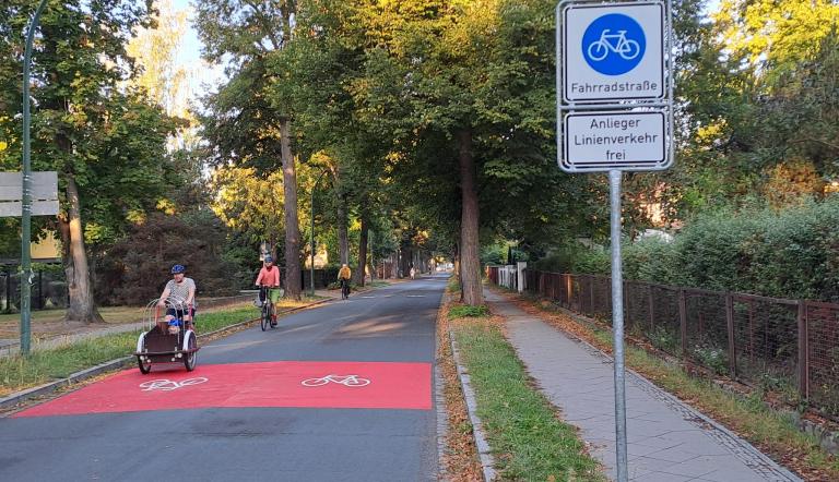 Rote Markierungen auf der Stahnsdorfer Straße und Verkehrsschilder zeigen den Beginn der Fahrradstraße an. 
