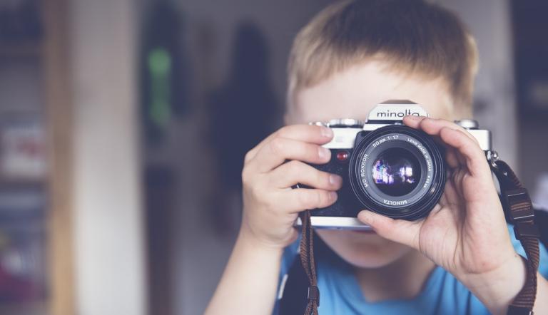 Ein Kind hält eine Kamera in der Hand und fotografiert die Person, die das Foto macht.