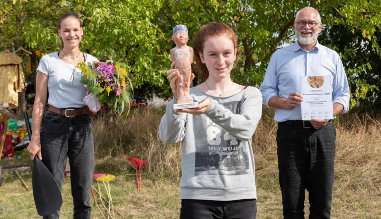 Lehrer und Schülerinnen des Evangelischen Gymnasiums Hermannswerder halten Blumen, Urkunde und Klimapreisskulptur in den Händen