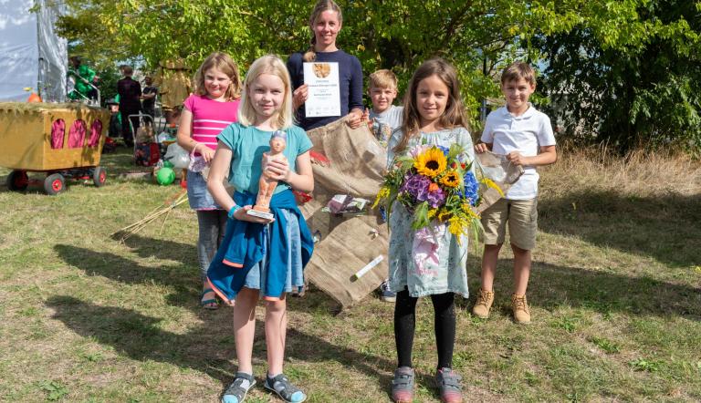 Lehrerin, Schülerinnen und Schüler der Karl-Foerster-Schule halten Blumen, Urkunde und Klimapreisskulptur in den Händen