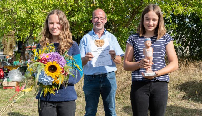 Lehrer und Schülerinnen der Montessori Oberschule Potsdam halten Blumen, Urkunde und Klimapreisskulptur in den Händen