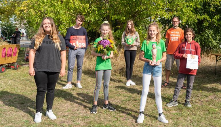 Lehrer, Schülerinnen und Schüler der Leonardo-da-Vinci-Gesamtschulehalten Blumen, Urkunde und Klimapreisskulptur in den Händen