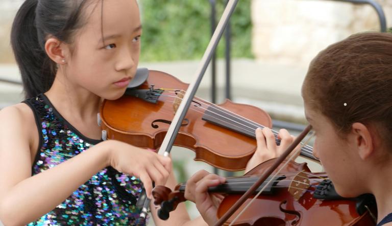 Zwei Junge Mädchen spielen Violine unter freiem Himmel