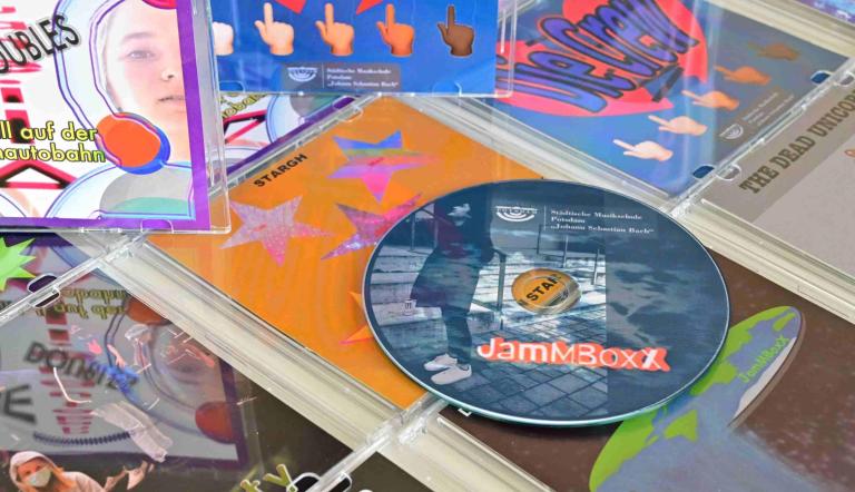 JamMBoxX 20-21 CD Präsentation - einige bunte - von Schüler:innen selbstgestaltete CD-Cover sind zu sehen