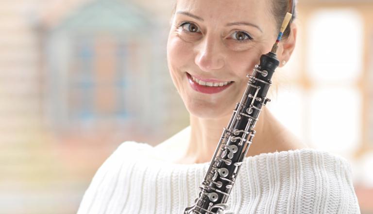 Eine Musikerin lächelt und hält ihre Oboe