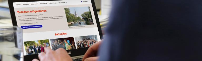 Notebook mit der Startseite von mitgestalten.potsdam.de Zu sehen ist ein Notebook mit der Startseite von mitgestalten.potsdam.de, vor dem eine Person sitzt und auf der Tastatur tippt.