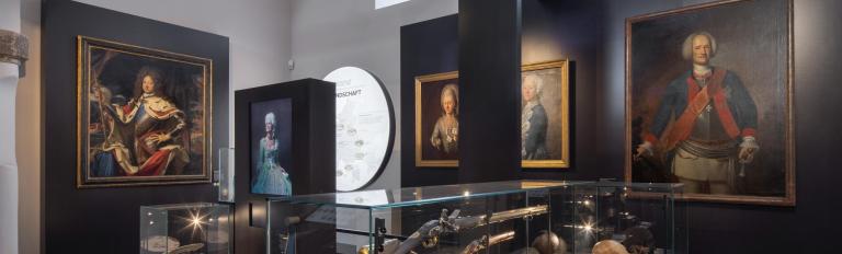 Das Foto zeigt einen Raum der Brandenburg - Ausstellung im Brandenburg Museum für Zukunft, Gegenwart und Geschichte. Zu sehen sind Gemälde und Vitrinen mit Ausstellungsstücken.